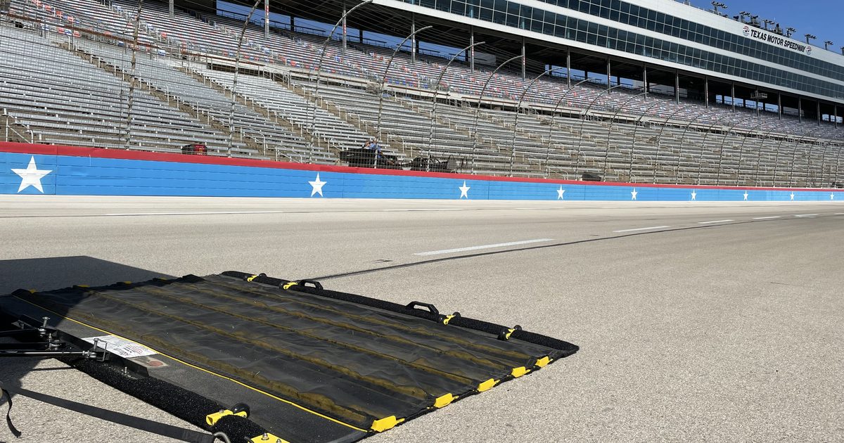 FOD-Razor friction sweeper towed across the apron at Texas Motor Speedway, with the speedway's branded grandstand and star wall visible in the background